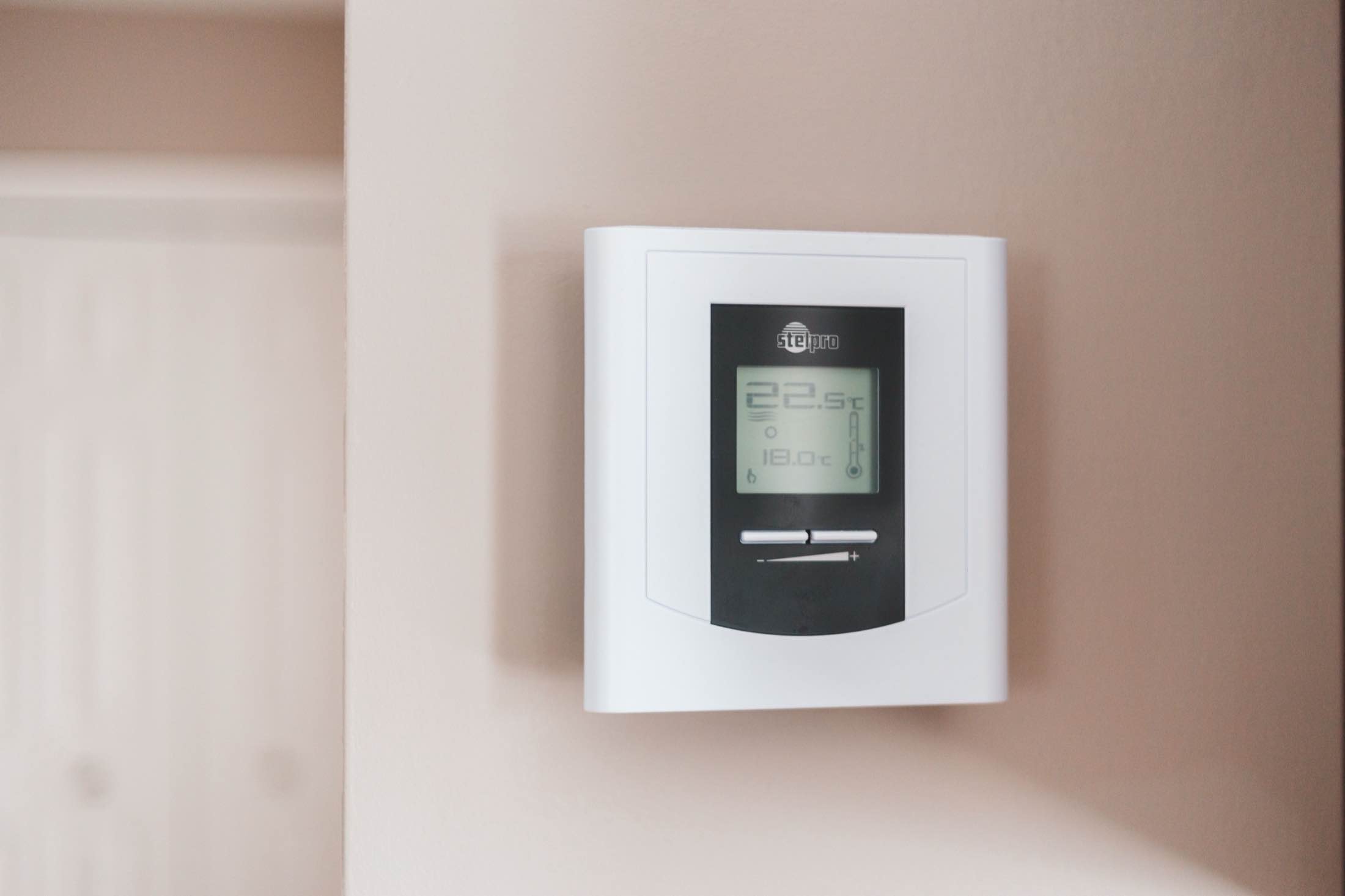 A digital wall-mounted thermostat on a pale wall
