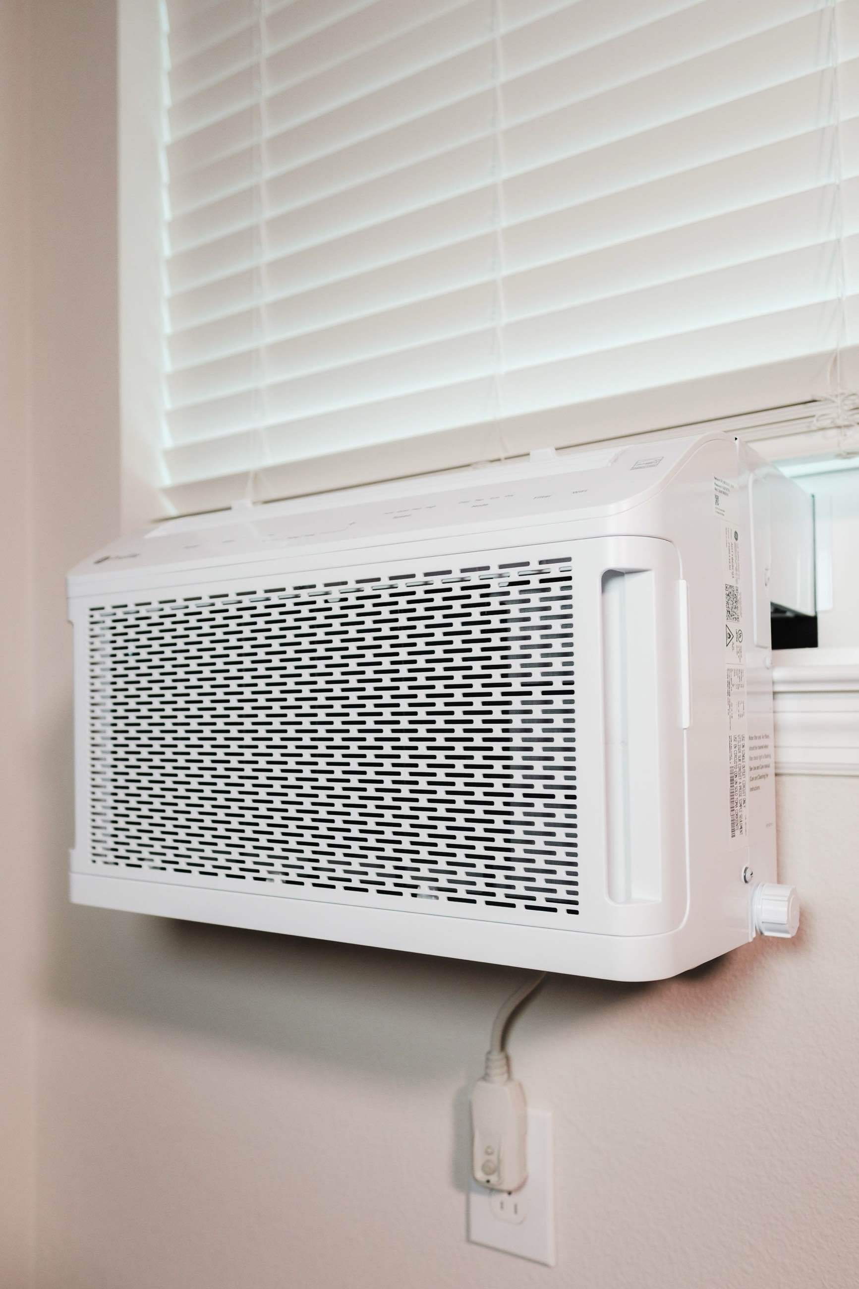 A wall-mounted indoor air-conditioning unit beneath a window