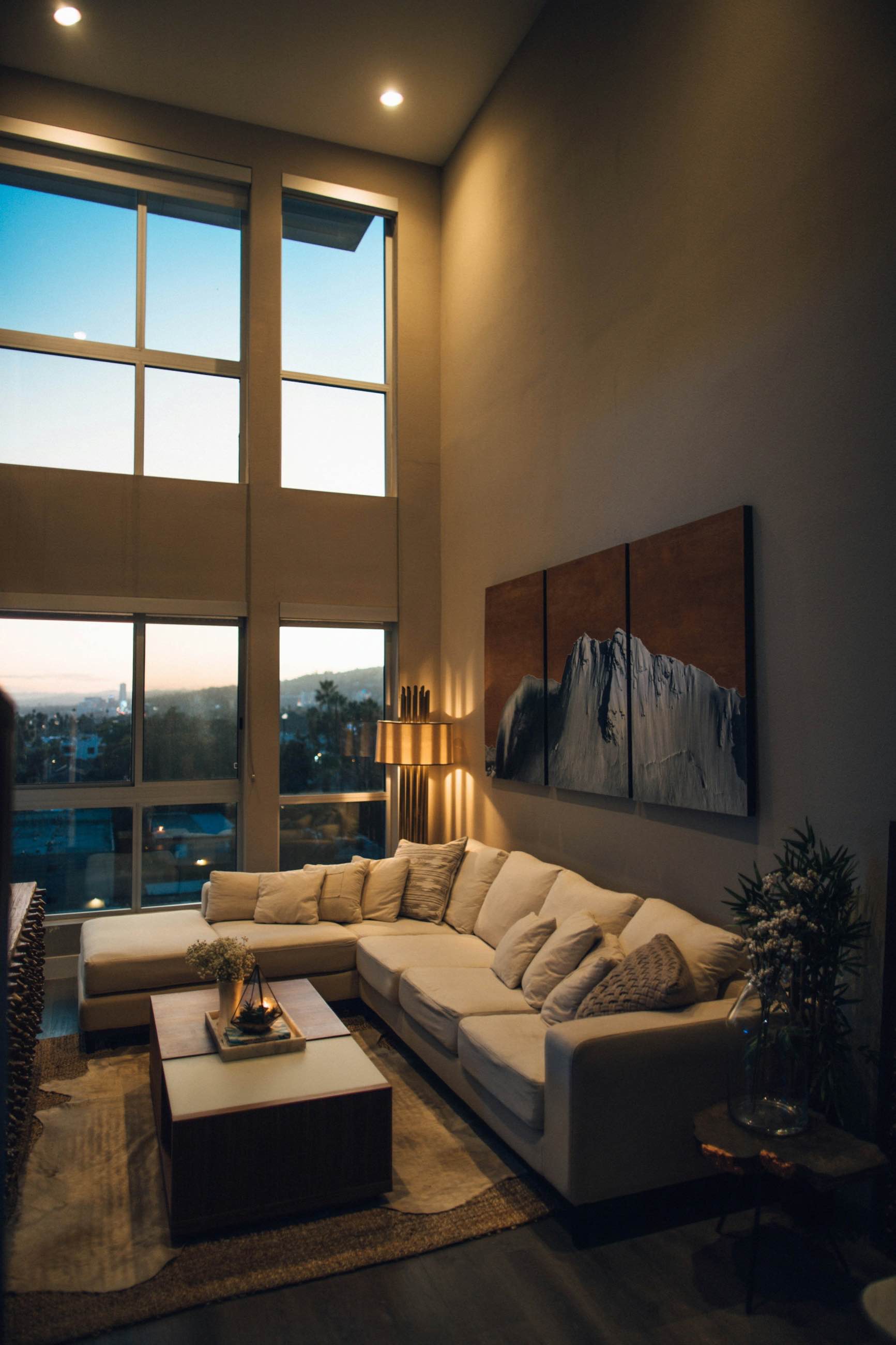 A double-height living room with tall windows at dusk