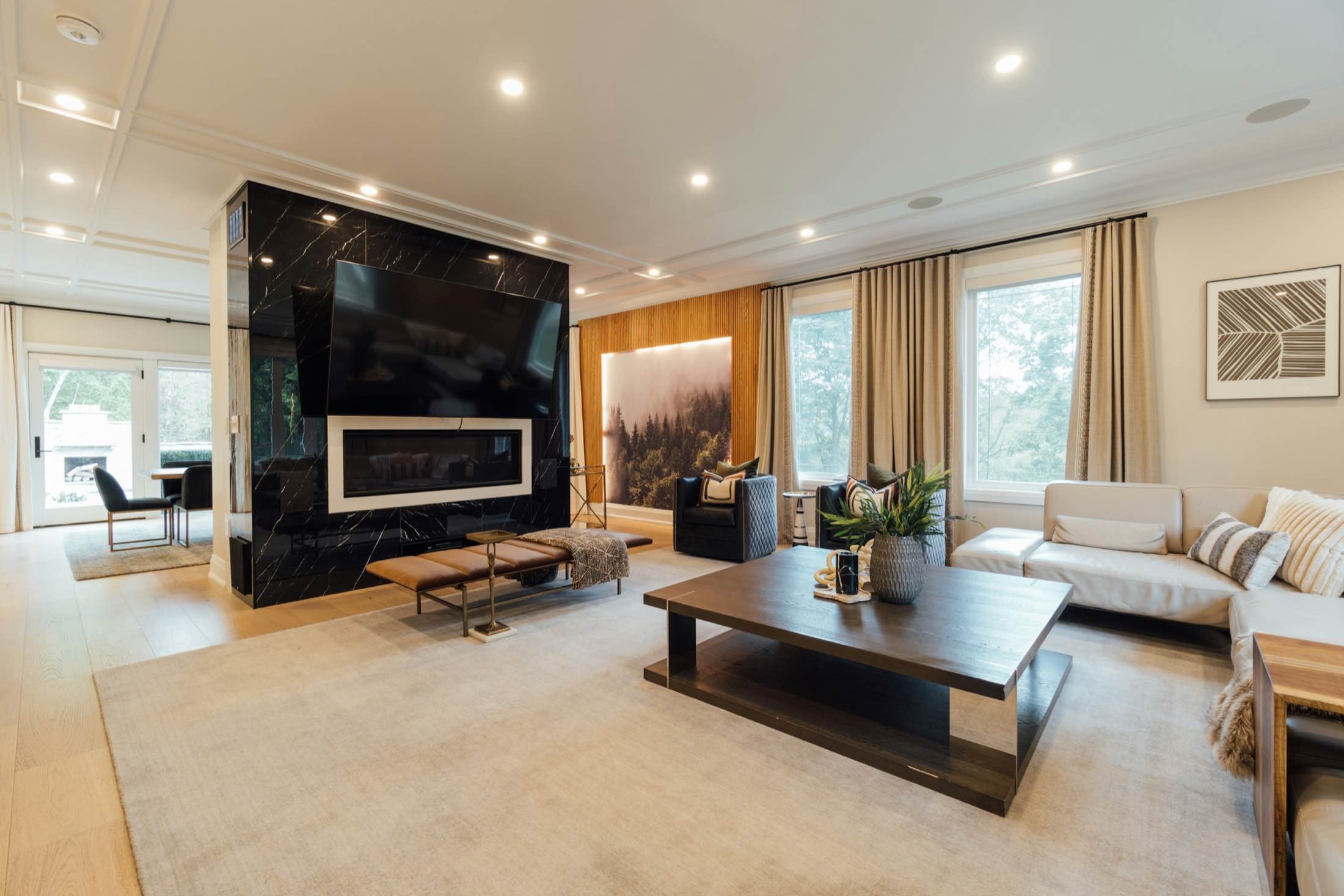 A bright living room with a black stone media wall and recessed ceiling lights