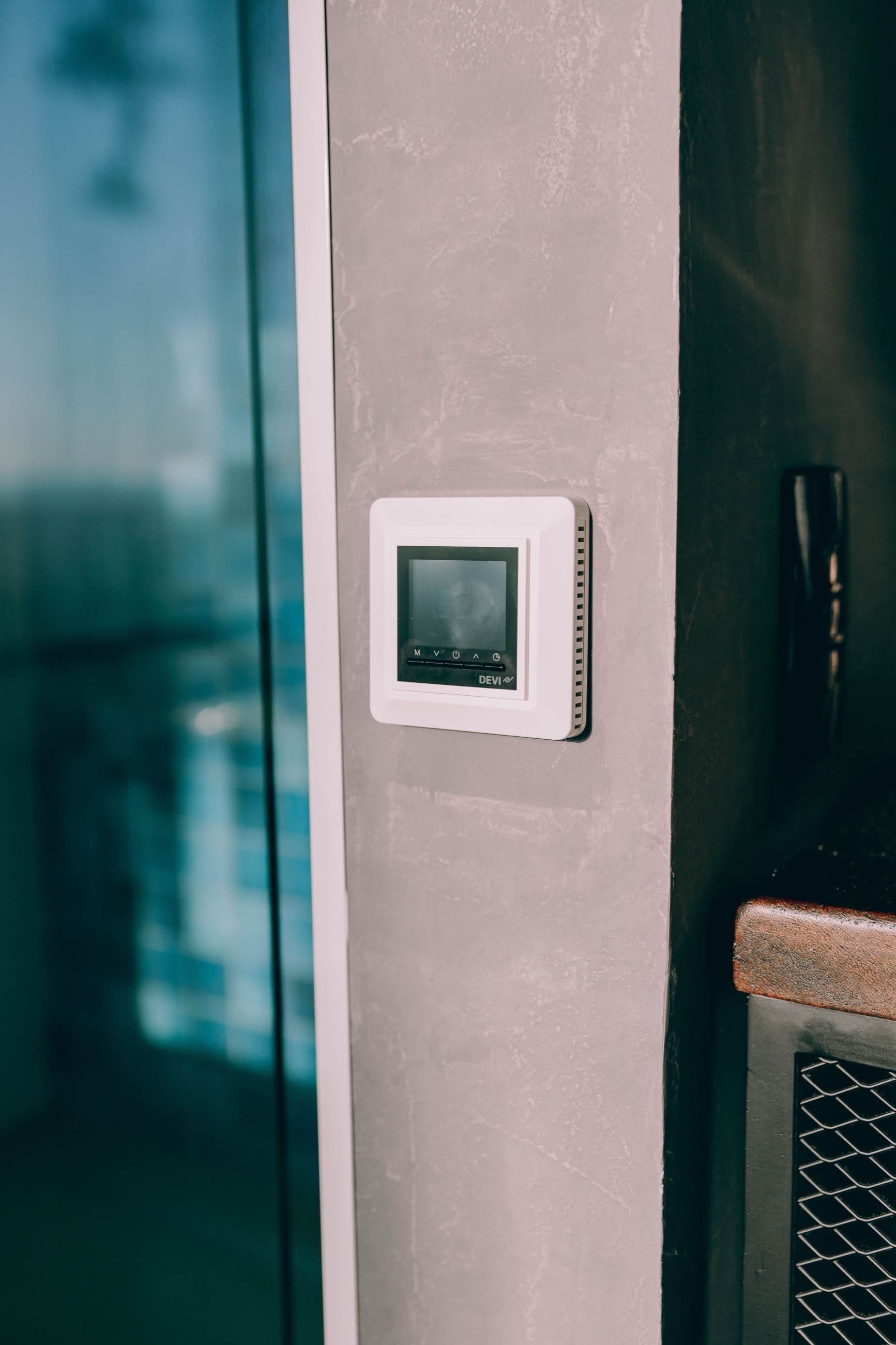 A slim digital wall control mounted beside a doorway