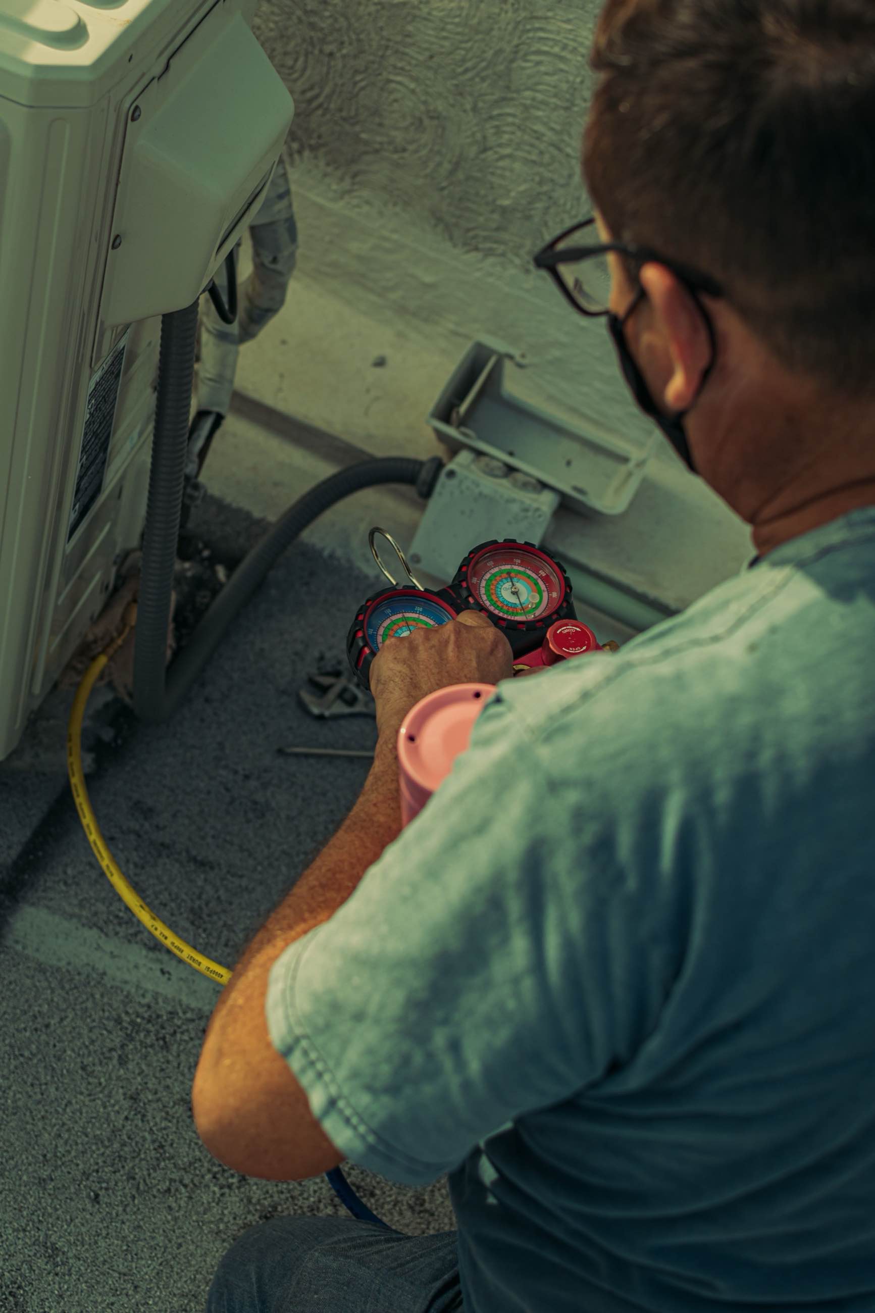 A technician holding a refrigerant gauge set during service